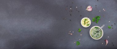 Salata sosu. Krema sosu ve baharatlı sarımsak yağı ve taze yeşillikler. Mutfak arka planı, siyah taş beton, düz döşeme, pankart biçimi