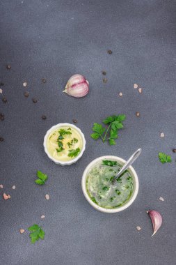 Salata sosu. Krema sosu ve baharatlı sarımsak yağı ve taze yeşillikler. Mutfak arka planı, siyah taş beton, düz döşeme, üst manzara