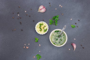 Salata sosu. Krema sosu ve baharatlı sarımsak yağı ve taze yeşillikler. Mutfak arka planı, siyah taş beton, düz döşeme, üst manzara