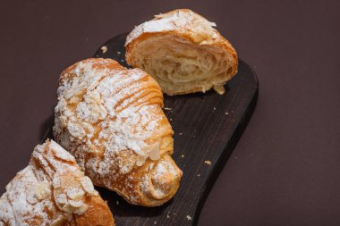 Günaydın konsepti. Krema dolgulu taze kruvasan ve badem gevreği. Tatlı tatlı, dekonstrüksiyon, seçici odaklanma, düz yatış, yakın çekim