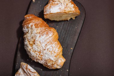 Günaydın konsepti. Krema dolgulu taze kruvasan ve badem gevreği. Tatlı tatlı, dekonstrüksiyon, seçici odaklanma, düz yatış, üst görünüm