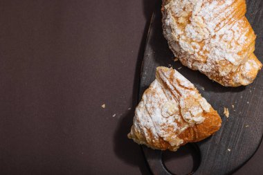 Günaydın konsepti. Krema dolgulu taze kruvasan ve badem gevreği. Tatlı tatlı, dekonstrüksiyon, seçici odaklanma, düz yatış, üst görünüm