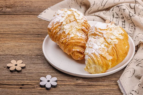 Good morning concept. Fresh croissants with cream filling and almond flakes. Sweet dessert, wooden background, copy space