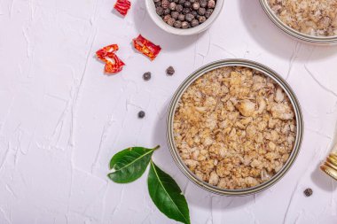 Baharat ve bitkilerle yağlı konserve balık ton balığı. Vejetaryen yaşam tarzı için sağlıklı malzeme. Deniz ürünleri, omega, düz yatak. Sert ışık, koyu gölge, beyaz alçı arka plan, üst görünüm