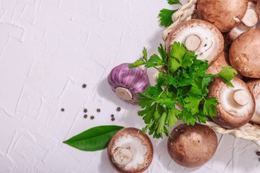 Ham kahverengi kraliyet şampiyonları sepette. Vejetaryen yemekleri pişirmek. Sarımsak, yeşillik, baharat, sert ışık, koyu gölge. Yenilebilir mantarlar, modern bir eğilim, beyaz arka plan, üst görünüm