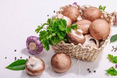 Ham kahverengi kraliyet şampiyonları sepette. Vejetaryen yemekleri pişirmek. Sarımsak, yeşillik, baharat, sert ışık, koyu gölge. Yenilebilir mantarlar, modern bir eğilim, beyaz arkaplan, kopyalama alanı