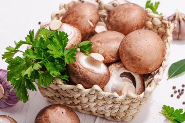 Ham kahverengi kraliyet şampiyonları sepette. Vejetaryen yemekleri pişirmek. Sarımsak, yeşillik, baharat, sert ışık, koyu gölge. Yenilebilir mantarlar, modern trend, beyaz arkaplan, kapat
