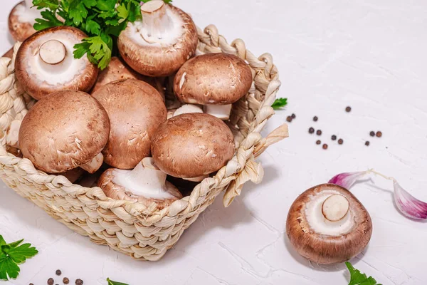 stock image Raw brown royal champignons in the basket. Cooking vegan food concept. Garlic, greens, spices, hard light, dark shadow. Edible mushrooms, a modern trend, white background, copy space