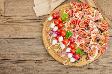 Şişe üzerinde piknik atıştırmalıkları. Jamon, mozzarella, kiraz domatesleri, bezelyeler, taze yeşiller. Modern duruş, ahşap arkaplan, üst manzara