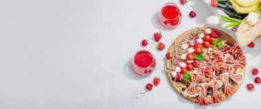 Piknik yemekleri konsepti. Şarap ve baget sepeti, şiş üzerinde aperatifler. Et, peynir, sebze, meyve ve çiçek buketi. Sert ışık, karanlık gölgeler, taş arkaplan, afiş biçimi