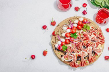 Piknik yemekleri konsepti. Şarap ve baget sepeti, şiş üzerinde aperatifler. Et, peynir, sebze, meyve ve çiçek buketi. Sert ışık, karanlık gölgeler, taş zemin, üst görünüm