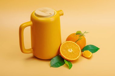 Seramik çay demliğinde portakal çayı ve olgun meyveler. Serinletici mevsimlik içecek, yeşil narenciye yapraklı kavramsal arka plan. Modern biçim, seçici odak, kopyalama alanı