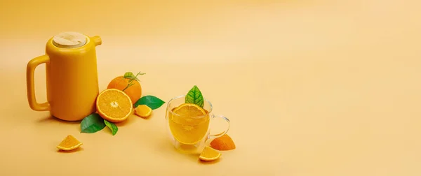 stock image Orange tea in ceramic tea pot with ripe fruits. Refreshment seasonal drink, conceptual background with green citrus leaves. Modern style, selective focus, copy space