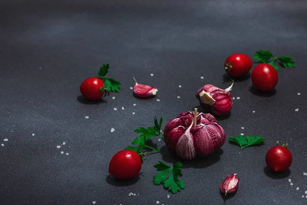 新鮮な野菜やハーブと料理の背景 トマトチェリー ニンニク パセリ フラットレイアウト ハードライト 暗い影 黒の石の具体的な背景 — ストック写真