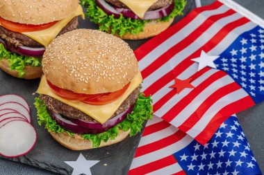 Ev yapımı hamburgerler. Amerikan klasiği, geleneksel piknik, parti ya da Bağımsızlık Günü yemeği. Sos, cips, tatlı mısır. Koyu taş beton arka plan, kapat