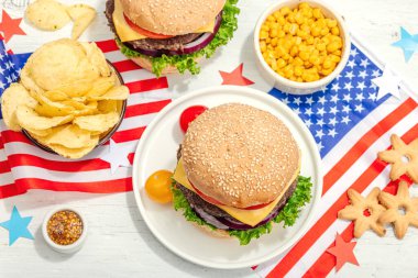 Ev yapımı hamburgerler. Amerikan klasiği, geleneksel piknik, parti ya da Bağımsızlık Günü yemeği. Sert ışık, karanlık gölge, düz yer, beyaz ahşap zemin, üst manzara