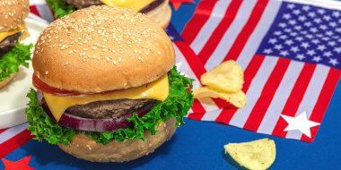 Ev yapımı hamburgerler. Amerikan klasiği, geleneksel piknik, parti ya da Bağımsızlık Günü yemeği. Sert ışık, koyu gölge, düz alan, mavi arkaplan, pankart biçimi