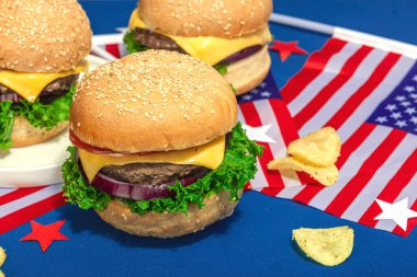 Ev yapımı hamburgerler. Amerikan klasiği, geleneksel piknik, parti ya da Bağımsızlık Günü yemeği. Sert ışık, koyu gölge, düz uzanma, mavi arkaplan, kapat