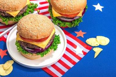 Ev yapımı hamburgerler. Amerikan klasiği, geleneksel piknik, parti ya da Bağımsızlık Günü yemeği. Sert ışık, koyu gölge, düz alan, mavi arkaplan, kopyalama alanı