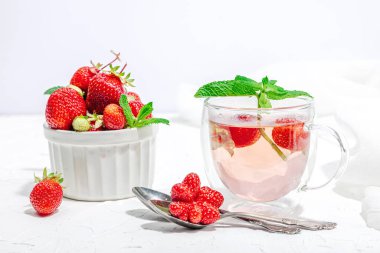 Çilek çayı konsepti. Günaydın konsepti. Çaydanlık, olgun meyve, sağlıklı içecek. Sert ışık, koyu gölge, beyaz arkaplan, kapat