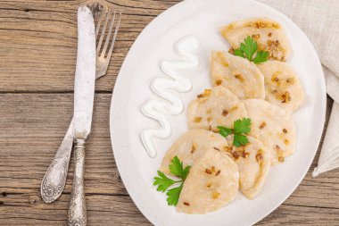 Lahanayla dolu börekler. Kızarmış soğan, taze ekşi krema. Geleneksel Ukrayna yemeği, moda vejetaryen yemekleri. Ahşap arkaplan, üst manzara