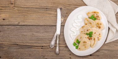 Lahanayla dolu börekler. Kızarmış soğan, taze ekşi krema. Geleneksel Ukrayna yemeği, moda vejetaryen yemekleri. Ahşap arkaplan, pankart biçimi