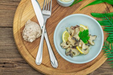 Yağlı, baharatlı ve yeşillikli Rapana istiridye eti. Sağlıklı deniz ürünleri omega açısından zengindir. Deniz dekoru, ahşap zemin, düz yatış, üst manzara.