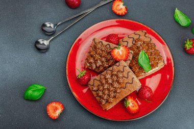 Taze çilekli lezzetli çikolatalı kekler. Tatlı tatlı, günaydın konsepti. Ev yapımı pişirme, krema, sos. Koyu taş zemin, üst görünüm