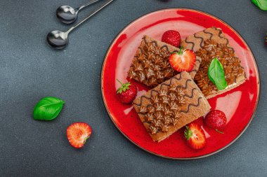 Taze çilekli lezzetli çikolatalı kekler. Tatlı tatlı, günaydın konsepti. Ev yapımı pişirme, krema, sos. Koyu taş zemin, üst görünüm