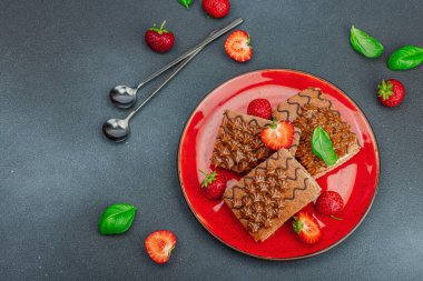 Taze çilekli lezzetli çikolatalı kekler. Tatlı tatlı, günaydın konsepti. Ev yapımı pişirme, krema, sos. Koyu taş arkaplan