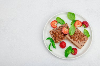 Taze çilekli lezzetli çikolatalı kekler. Tatlı tatlı, günaydın konsepti. Ev yapımı pişirme, krema, sos. Hafif taş arkaplan, üst görünüm