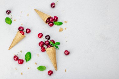 Hafif beton arka planda vişneli waffle külahları. Düz yatak, eski peçete, geleneksel dondurma yaz konsepti.