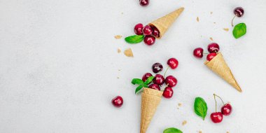 Hafif beton arka planda vişneli waffle külahları. Düz yatak, eski peçete, geleneksel dondurma yaz konsepti, afiş biçimi