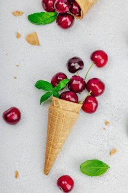 Hafif beton arka planda vişneli waffle külahları. Düz yatak, eski peçete, geleneksel dondurma yaz konsepti, üst manzara.