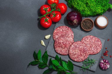 Çiğ hamburger köftesi. Taze et, baharat, sebze ve otlar. Ev yapımı Amerikan klasiği, geleneksel piknik, parti ya da Bağımsızlık Günü yemekleri. Koyu taş zemin, üst görünüm