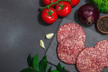 Çiğ hamburger köftesi. Taze et, baharat, sebze ve otlar. Ev yapımı Amerikan klasiği, geleneksel piknik, parti ya da Bağımsızlık Günü yemekleri. Koyu taş zemin, üst görünüm