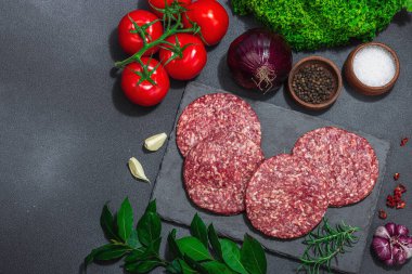 Çiğ hamburger köftesi. Taze et, baharat, sebze ve otlar. Ev yapımı Amerikan klasiği, geleneksel piknik, parti ya da Bağımsızlık Günü yemekleri. Koyu taş zemin, üst görünüm