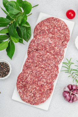 Çiğ hamburger köftesi. Taze et, baharat, sebze ve otlar. Ev yapımı Amerikan klasiği, geleneksel piknik, parti ya da Bağımsızlık Günü yemekleri. Hafif taş arkaplan, üst görünüm