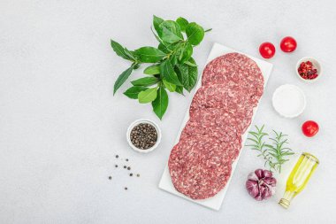Çiğ hamburger köftesi. Taze et, baharat, sebze ve otlar. Ev yapımı Amerikan klasiği, geleneksel piknik, parti ya da Bağımsızlık Günü yemekleri. Hafif taş arkaplan, üst görünüm