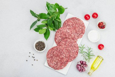 Çiğ hamburger köftesi. Taze et, baharat, sebze ve otlar. Ev yapımı Amerikan klasiği, geleneksel piknik, parti ya da Bağımsızlık Günü yemekleri. Hafif taş arkaplan, üst görünüm