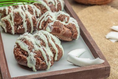 Profiterol choux hamur çörekleri ve hindistan cevizi kreması tropikal olarak servis edilir. Palmiye yaprakları, tatlı, sağlıklı tatlı, düz uzanma, yakın çekim.