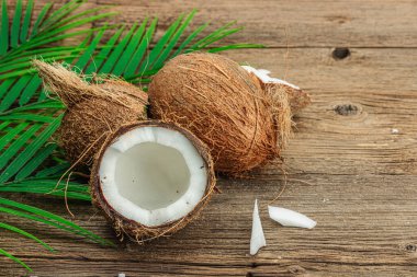 Hindistan cevizi ve palmiye yapraklarıyla yaz tropik arka plan. Geleneksel dekor, desenli meyve, yolculuk konsepti. Eski tahta zemin, düz yatış, kopyalama alanı