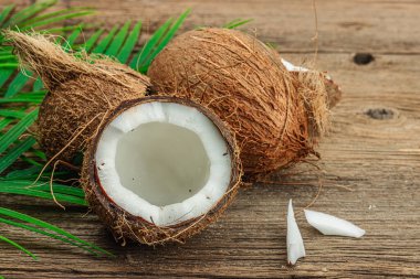 Hindistan cevizi ve palmiye yapraklarıyla yaz tropik arka plan. Geleneksel dekor, desenli meyve, yolculuk konsepti. Eski tahta arka plan, düz yatak, yakın çekim.