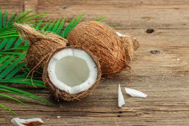 Hindistan cevizi ve palmiye yapraklarıyla yaz tropik arka plan. Geleneksel dekor, desenli meyve, yolculuk konsepti. Eski tahta zemin, düz yatış, kopyalama alanı