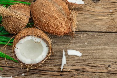 Hindistan cevizi ve palmiye yapraklarıyla yaz tropik arka plan. Geleneksel dekor, desenli meyve, yolculuk konsepti. Eski tahta zemin, düz yatış, üst manzara