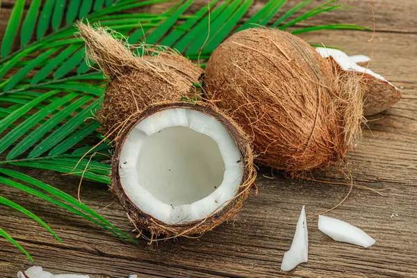 stock image Summer tropical background with coconuts and palm leaves. Traditional decor, textured fruit, voyage concept. Old wooden boards background, flat lay, close up