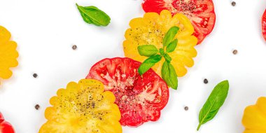 Beyaz arka planda izole edilmiş renkli aile yadigarı domates hasadı. Taze fesleğen yapraklarıyla olgunlaşmış sebzeler. Yaz salatası ve baharatları için sulu malzeme, düz döşeme, afiş biçimi