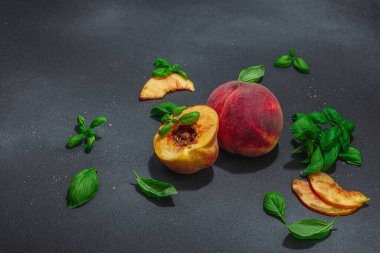 Meyve aşçılığı geçmişi. Olgun şeftali ve taze fesleğen yaprağı. Modern sert ışık, karanlık gölge, düz yatış, kopyalama alanı