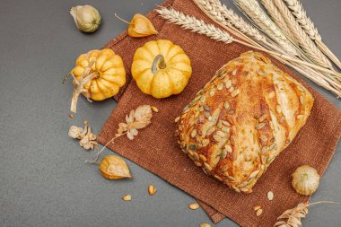 Balkabağı tohumlu taze ekmek. Ev yapımı konsept. Sonbahar dekoru, balkabağım, sonbahar yaprakları. Siyah taş zemin, düz zemin, üst manzara