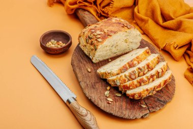 Balkabağı tohumlu taze ekmek. Ev yapımı konsept. Sonbahar dekoru, balkabağım, sonbahar yaprakları. Tahta kesme tahtası, pastel bej arkaplan, kopyalama alanı